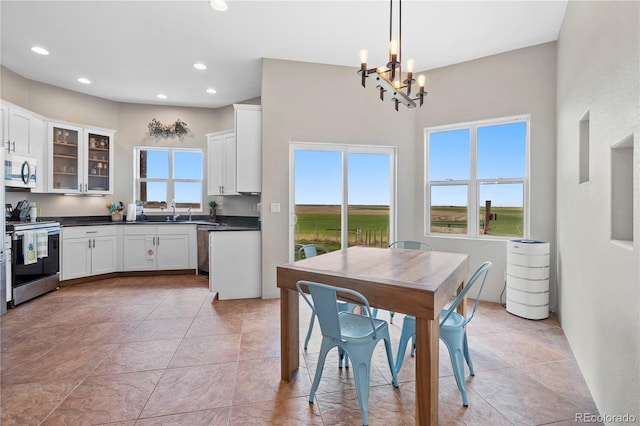 kitchen with white cabinets, stainless steel appliances, hanging light fixtures, and a notable chandelier