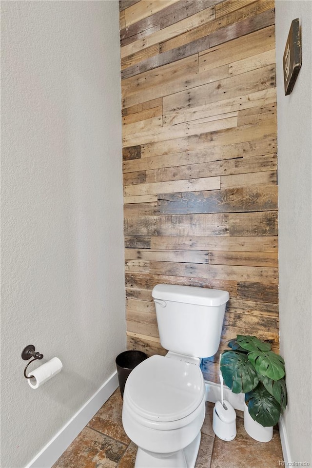 bathroom featuring toilet and wooden walls