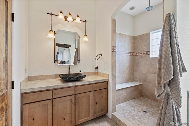 bathroom with a tile shower, vanity, and tile patterned floors