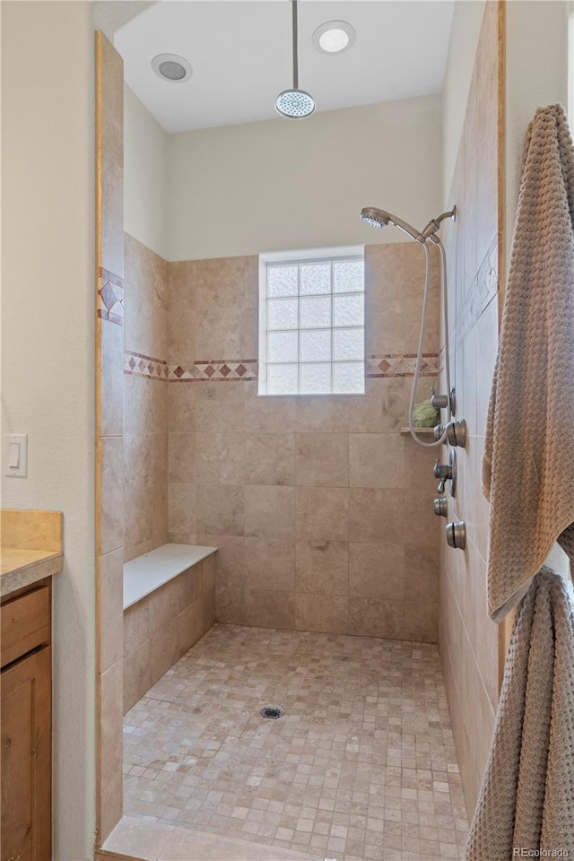 bathroom with a tile shower and vanity