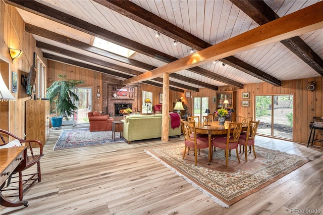 dining space featuring wood finished floors, plenty of natural light, a fireplace, and wooden walls