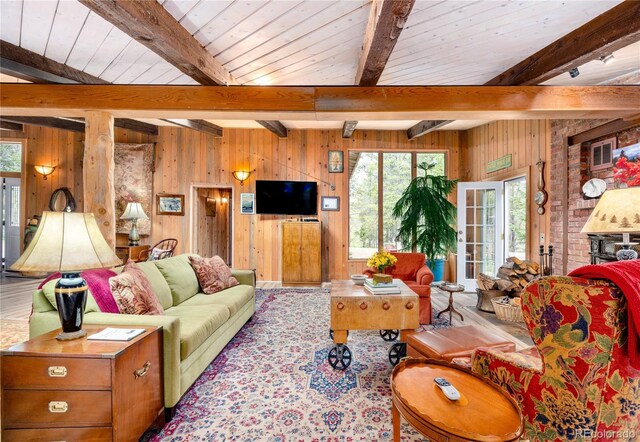 living room featuring wooden walls, beam ceiling, french doors, and brick wall