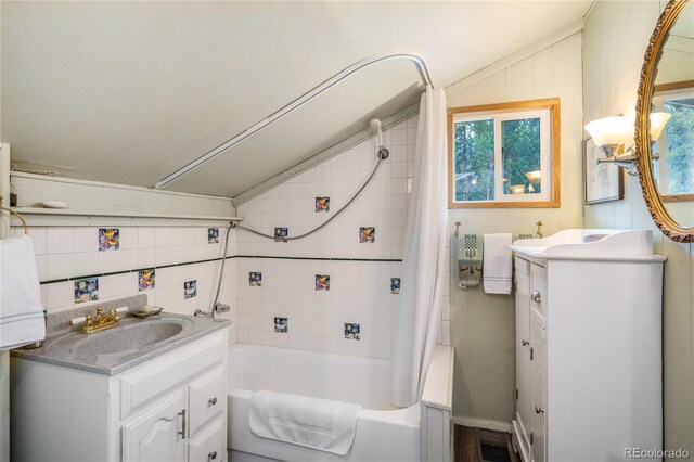 bathroom with tile walls, shower / tub combo, vanity, and vaulted ceiling