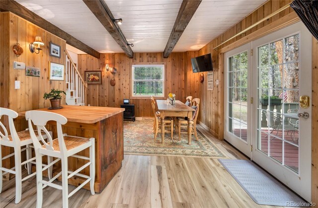 interior space with beam ceiling, a wealth of natural light, wooden walls, and light wood-type flooring