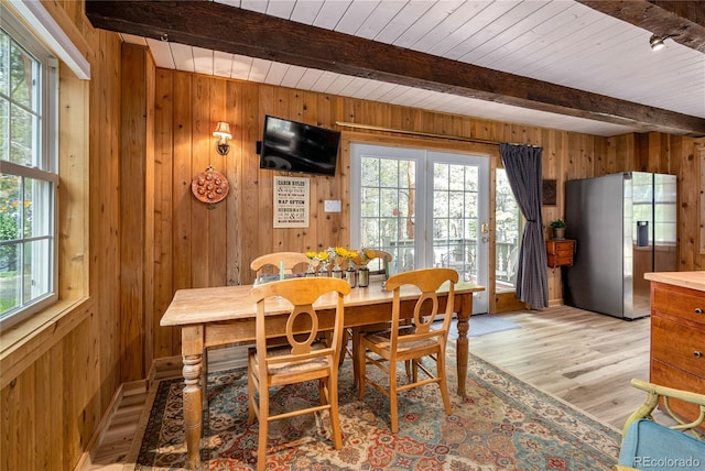 dining area featuring beamed ceiling, a wealth of natural light, and wooden walls