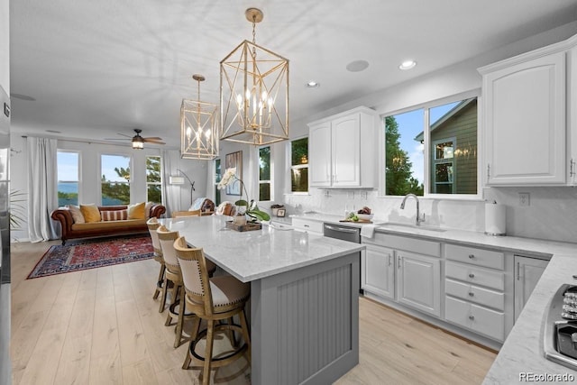 10837 Fox Sedge Way, Highlands Ranch, CO 80126 - kitchen with light stone counters, white cabinets, a kitchen island, a kitchen bar, and tasteful backsplash