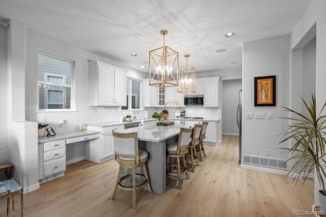 10837 Fox Sedge Way, Highlands Ranch, CO 80126 - kitchen featuring stainless steel microwave, white cabinets, a center island, a kitchen bar, and recessed lighting