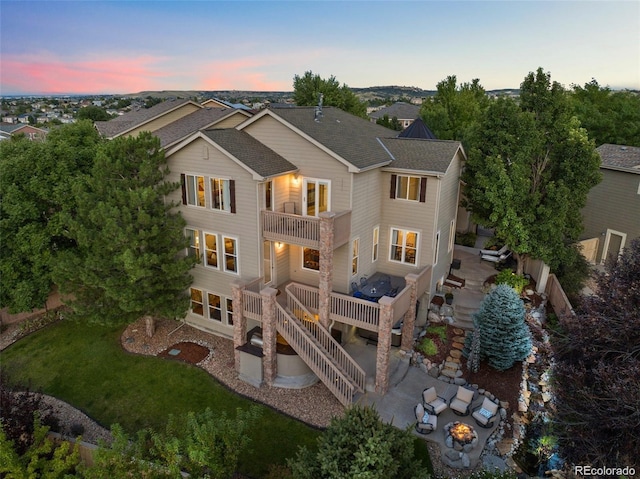 10837 Fox Sedge Way, Highlands Ranch, CO 80126 - back of property at dusk featuring a fire pit, a balcony, a patio, roof with shingles, and a lawn