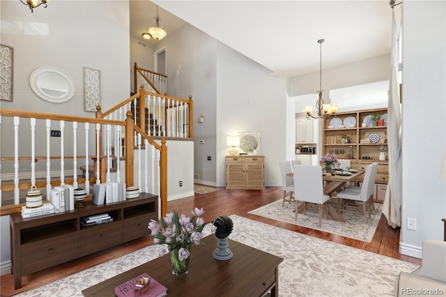 living room featuring a towering ceiling, dark wood-type flooring, and a notable chandelier