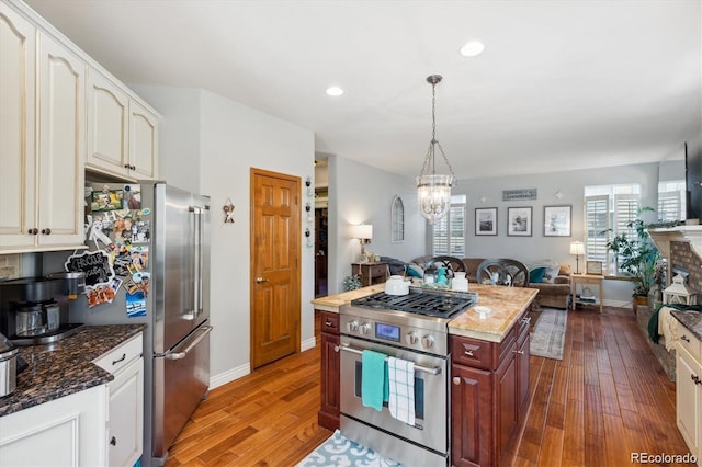 kitchen featuring dark stone countertops, appliances with stainless steel finishes, decorative light fixtures, dark hardwood / wood-style flooring, and a chandelier