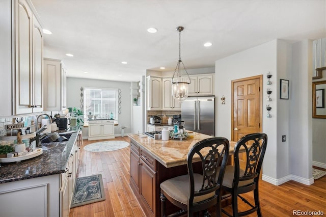 kitchen featuring high end fridge, a center island, dark stone counters, and light wood-type flooring