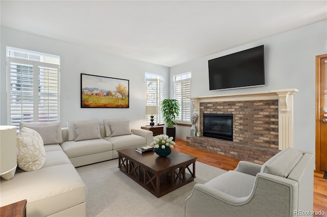 living room with a brick fireplace and light hardwood / wood-style flooring