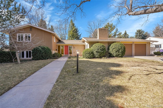 view of front of home with a chimney, a front lawn, concrete driveway, a garage, and brick siding