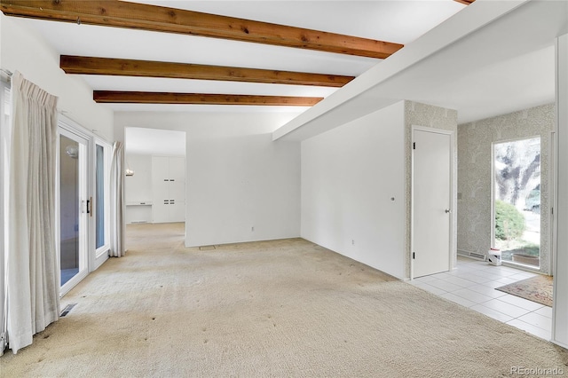 spare room featuring light carpet, beamed ceiling, visible vents, and light tile patterned flooring