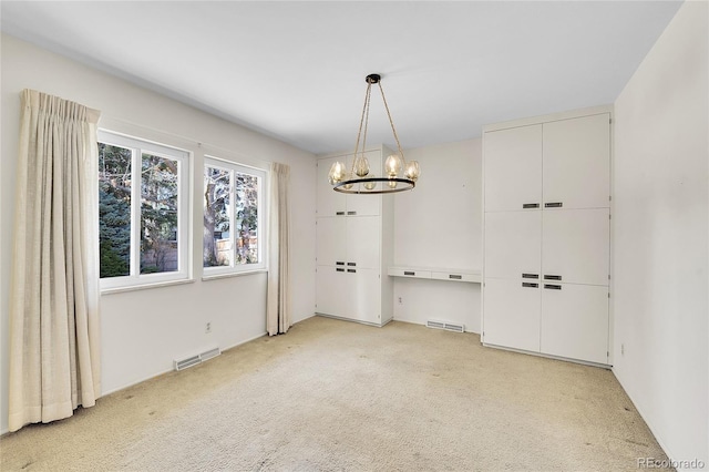 unfurnished dining area featuring an inviting chandelier, visible vents, and light carpet