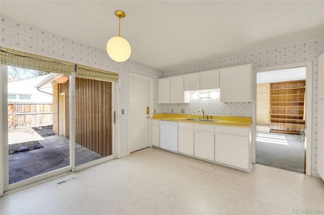 kitchen featuring visible vents, wallpapered walls, dishwasher, white cabinetry, and a sink