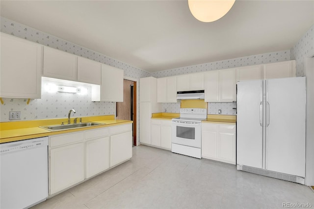 kitchen featuring under cabinet range hood, white appliances, wallpapered walls, and a sink