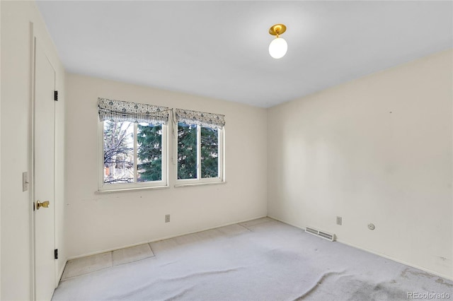 spare room with light carpet, visible vents, and baseboards