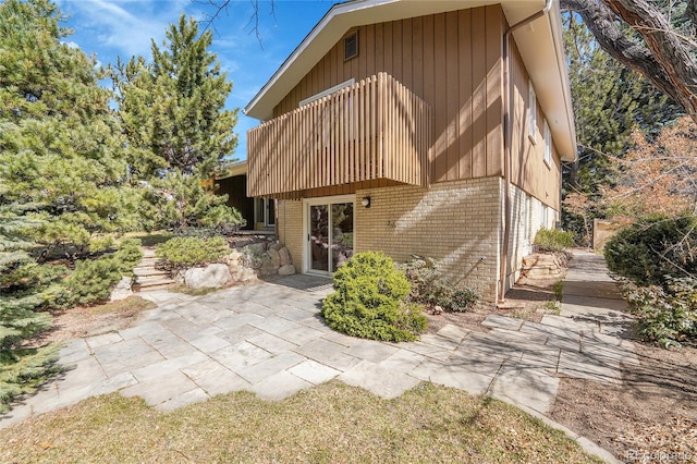 rear view of property with brick siding, a patio area, and a balcony