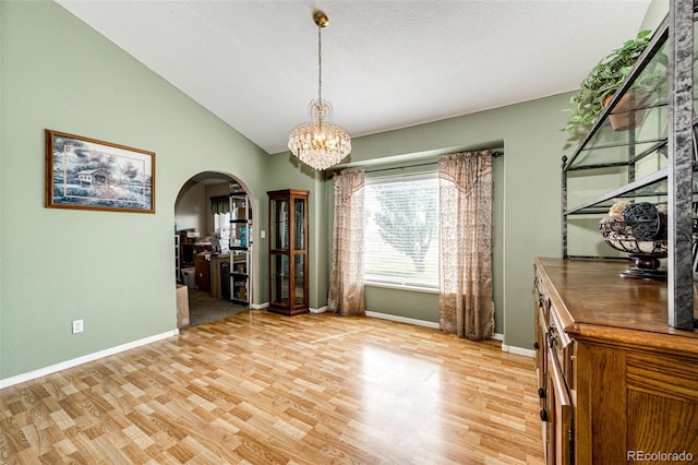 unfurnished dining area featuring a chandelier, light hardwood / wood-style floors, and vaulted ceiling