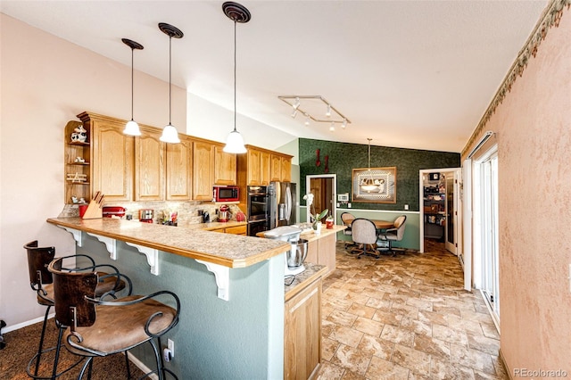 kitchen featuring pendant lighting, a breakfast bar, kitchen peninsula, and lofted ceiling