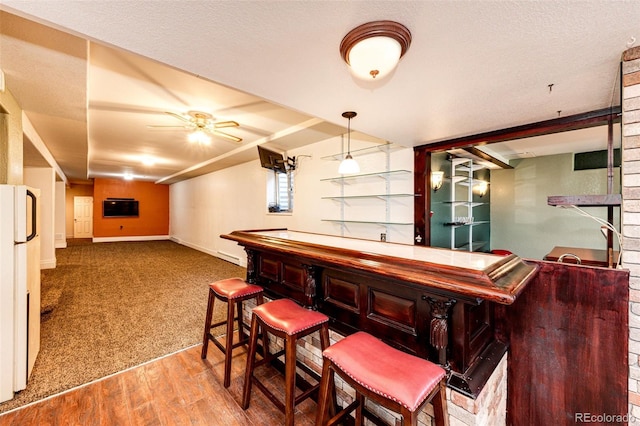 bar with hanging light fixtures, light hardwood / wood-style flooring, ceiling fan, baseboard heating, and white fridge