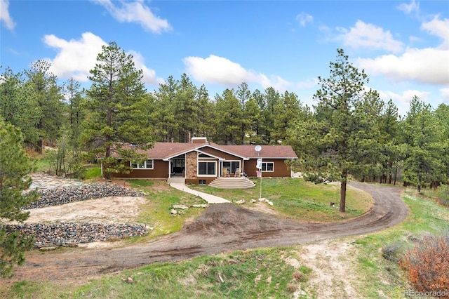 view of front of property with a chimney, driveway, and a front lawn