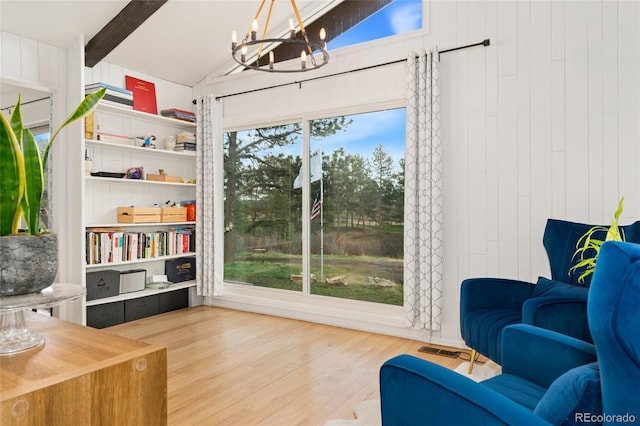 sitting room featuring a chandelier, lofted ceiling with beams, wood finished floors, and a healthy amount of sunlight