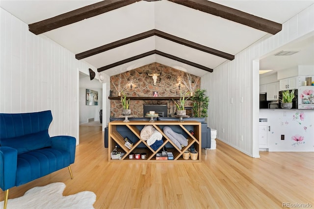 living area featuring visible vents, lofted ceiling with beams, and light wood-style floors