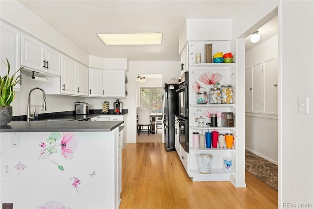 kitchen featuring dark countertops, a sink, white cabinets, freestanding refrigerator, and light wood-style floors