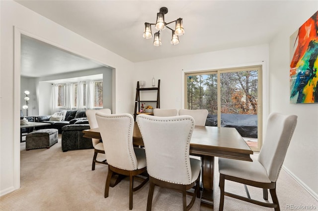 dining space with baseboards, a notable chandelier, and light carpet