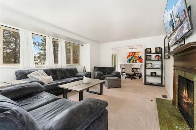 carpeted living area with an inviting chandelier, a fireplace with flush hearth, and visible vents