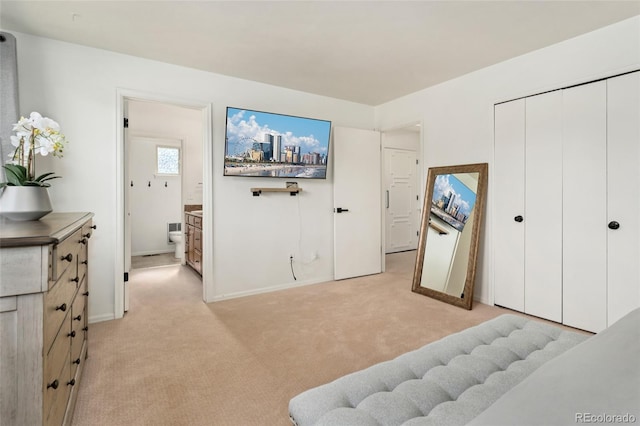 bedroom with light colored carpet, connected bathroom, baseboards, and a closet