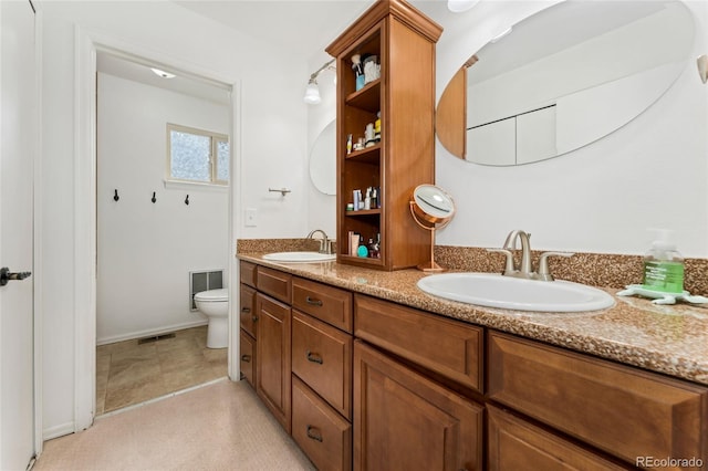 bathroom featuring a sink, toilet, double vanity, and visible vents