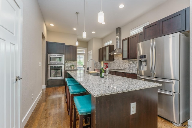 2868 Kingston St, Denver, CO 80238 - kitchen with appliances with stainless steel finishes, wall chimney exhaust hood, decorative backsplash, dark wood-type flooring, and dark brown cabinetry
