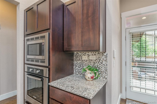 2868 Kingston St, Denver, CO 80238 - kitchen featuring appliances with stainless steel finishes, backsplash, light stone countertops, a textured wall, and wood finished floors