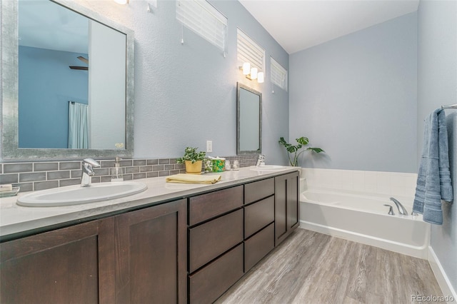 2868 Kingston St, Denver, CO 80238 - full bath featuring wood finished floors, double vanity, a garden tub, and backsplash