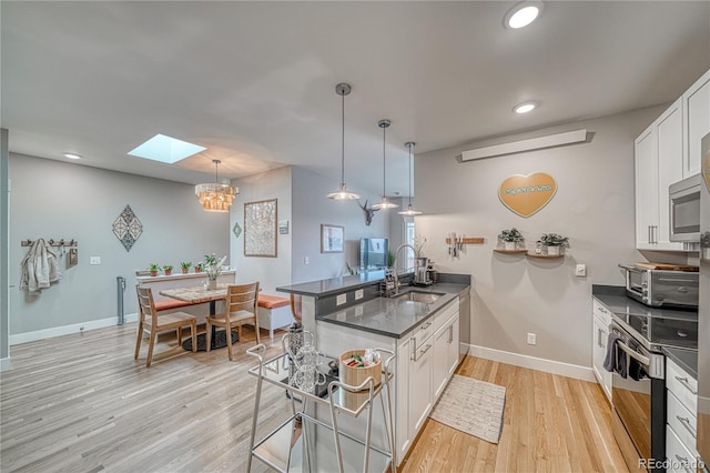 114 Old Stage Rd Unit D, Salida, CO 81201 - kitchen featuring stainless steel appliances, a peninsula, a skylight, dark countertops, and a sink