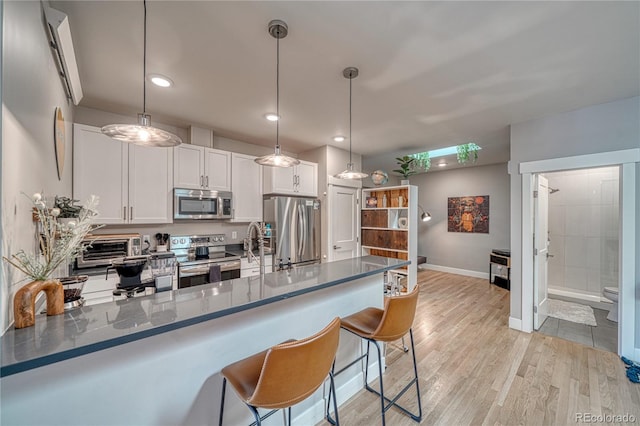 114 Old Stage Rd Unit D, Salida, CO 81201 - kitchen featuring appliances with stainless steel finishes, a peninsula, light wood-style floors, baseboards, and white cabinetry