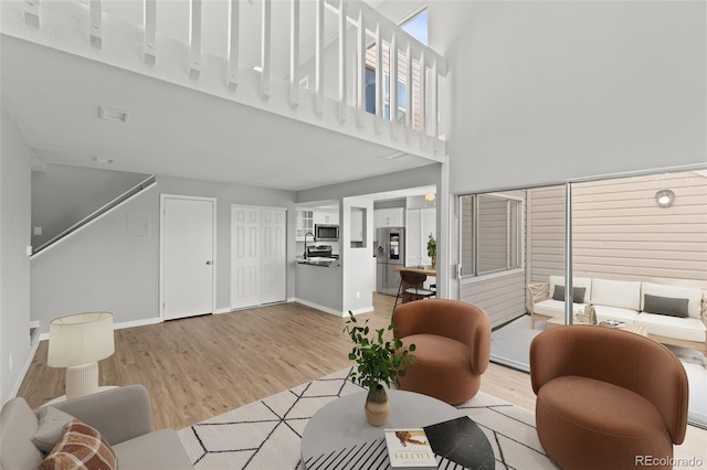 13633 E Yale Ave Unit B, Aurora, CO 80015 - living room with light wood-type flooring, baseboards, and a towering ceiling