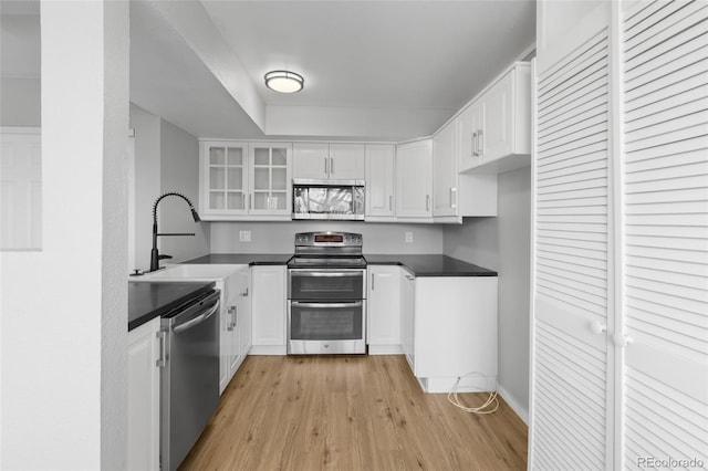 13633 E Yale Ave Unit B, Aurora, CO 80015 - kitchen with appliances with stainless steel finishes, a sink, dark countertops, light wood-style floors, and white cabinetry