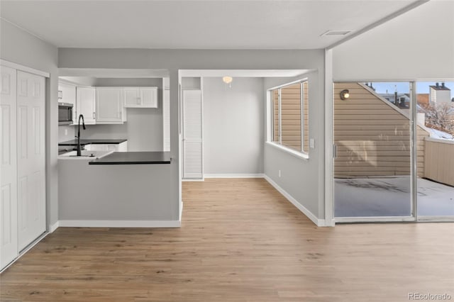 13633 E Yale Ave Unit B, Aurora, CO 80015 - kitchen featuring stainless steel microwave, white cabinets, light wood-type flooring, and baseboards