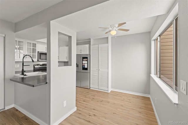 13633 E Yale Ave Unit B, Aurora, CO 80015 - kitchen with stainless steel appliances, white cabinets, a ceiling fan, light wood-style flooring, and baseboards