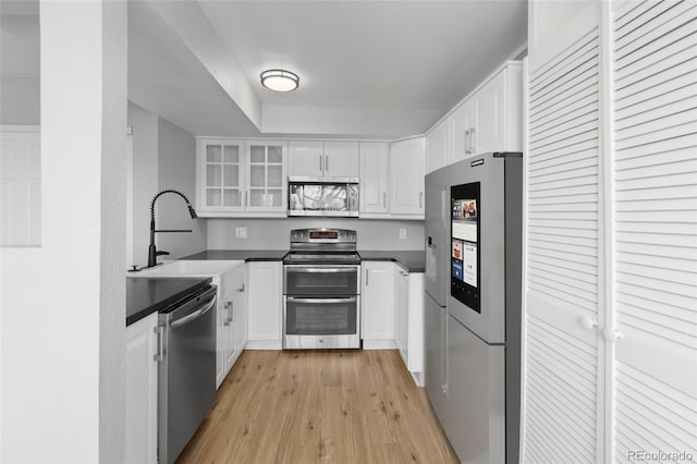 13633 E Yale Ave Unit B, Aurora, CO 80015 - kitchen with appliances with stainless steel finishes, a sink, light wood-type flooring, white cabinets, and glass insert cabinets