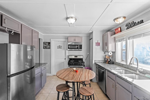 kitchen with sink, light stone countertops, stainless steel appliances, and light tile patterned floors