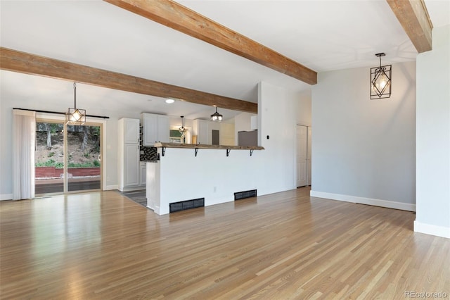 813 Panorama Dr, Colorado Springs, CO 80904 - unfurnished living room with baseboards, beamed ceiling, and light wood-style flooring