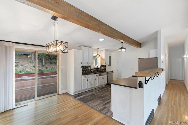 813 Panorama Dr, Colorado Springs, CO 80904 - kitchen with stainless steel dishwasher, dark countertops, refrigerator, light wood-type flooring, and beamed ceiling