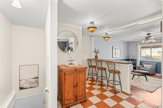 kitchen with decorative light fixtures, a kitchen bar, ceiling fan, and kitchen peninsula