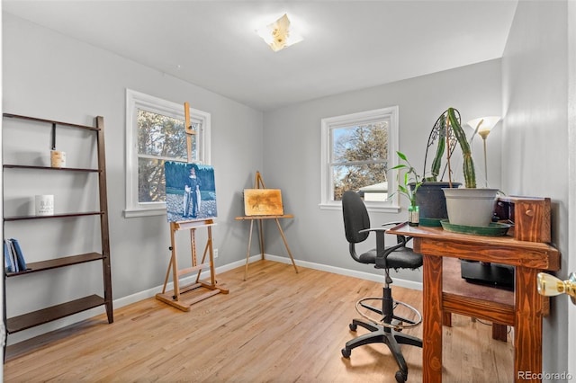 home office with light wood-type flooring and a healthy amount of sunlight