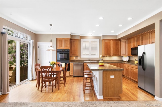 10633 Wynspire Way, Highlands Ranch, CO 80130 - kitchen featuring black appliances, a kitchen island, light wood finished floors, a breakfast bar area, and brown cabinetry